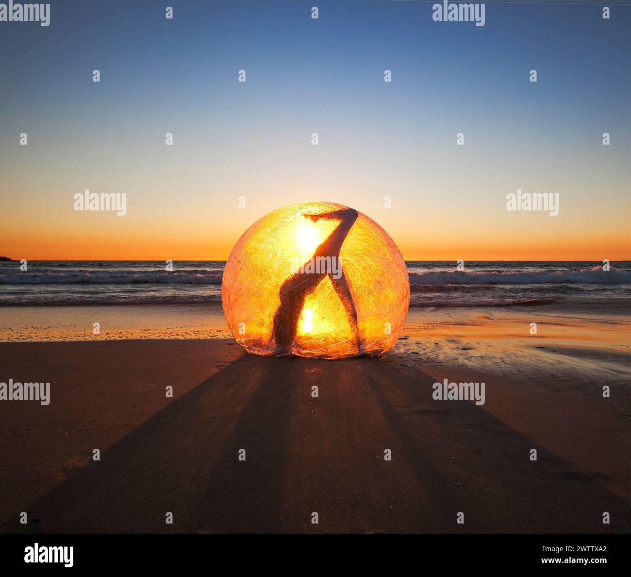 Silhouette of a person in a round glowing orb at sunset Stock Photo
