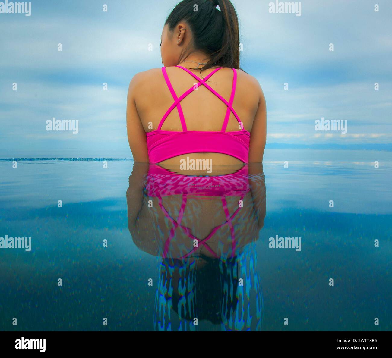 Woman standing in serene water at dusk Stock Photo