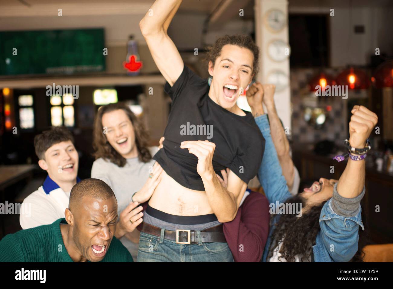 Group of friends celebrating excitedly in a bar Stock Photo
