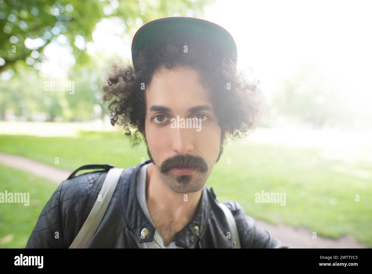 Man with curly hair wearing a cap outdoors Stock Photo