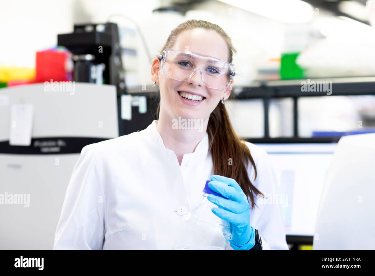 Smiling female scientist in lab coat conducting research in a laboratory. Stock Photo