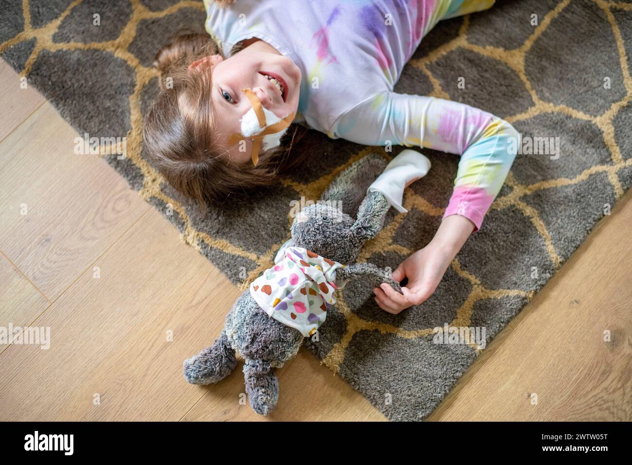 Young girl lying on the floor with her stuffed bunny by her side Stock Photo