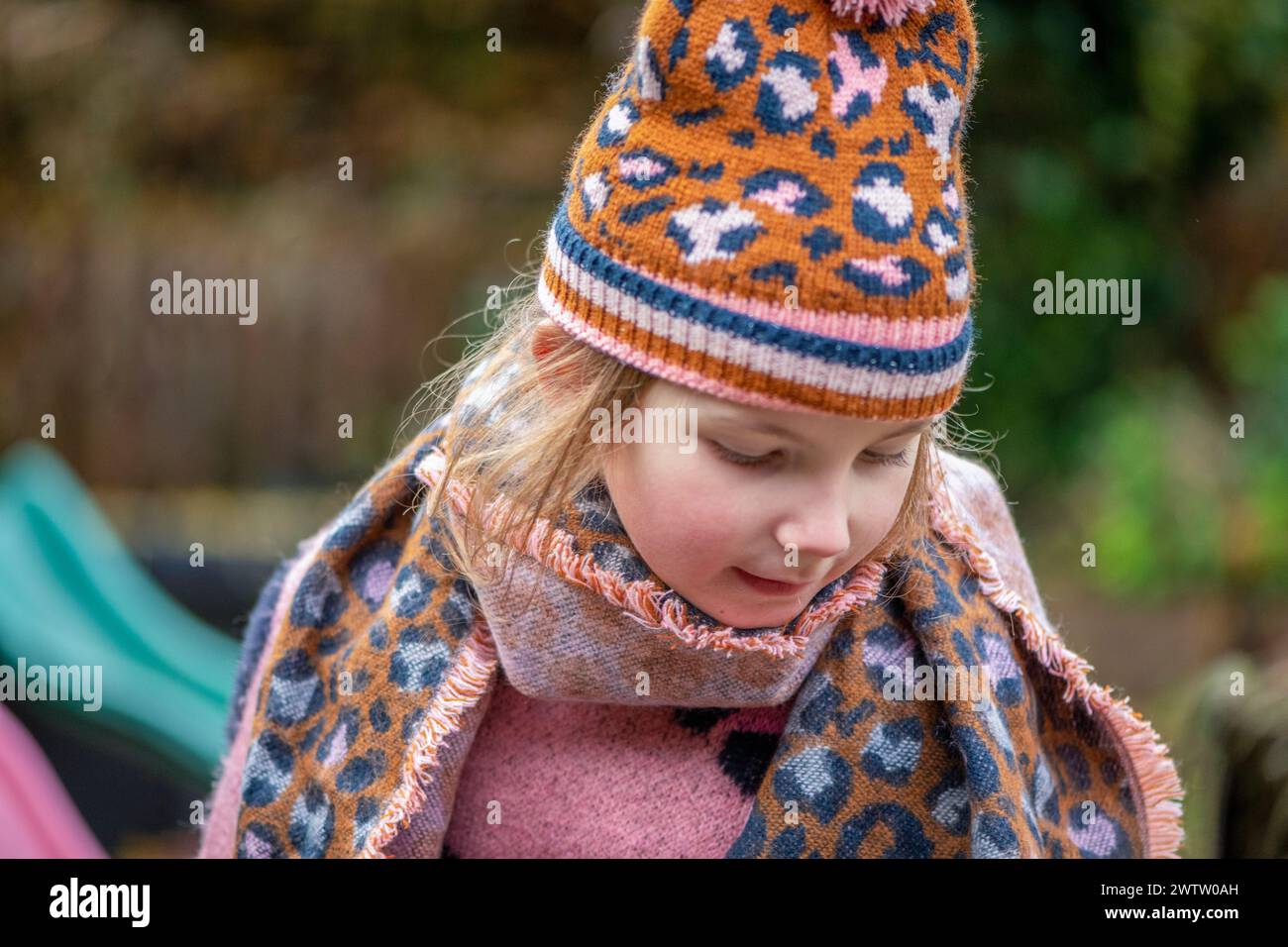 Child in a patterned hat and scarf outdoors Stock Photo