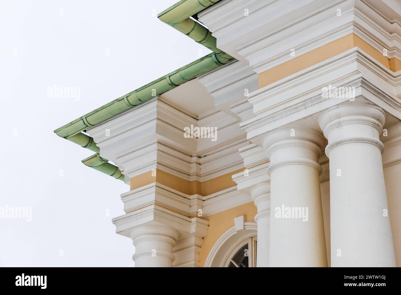 Classical portico with yellow and white details under green roof. Pillars and corners Stock Photo