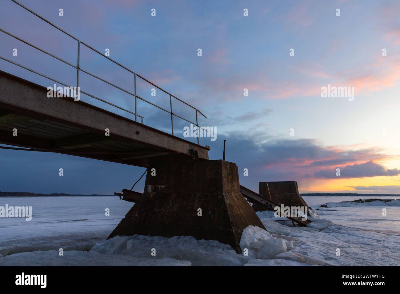 Old broken pier is under sunset sky on a winter evening, perspective view Stock Photo