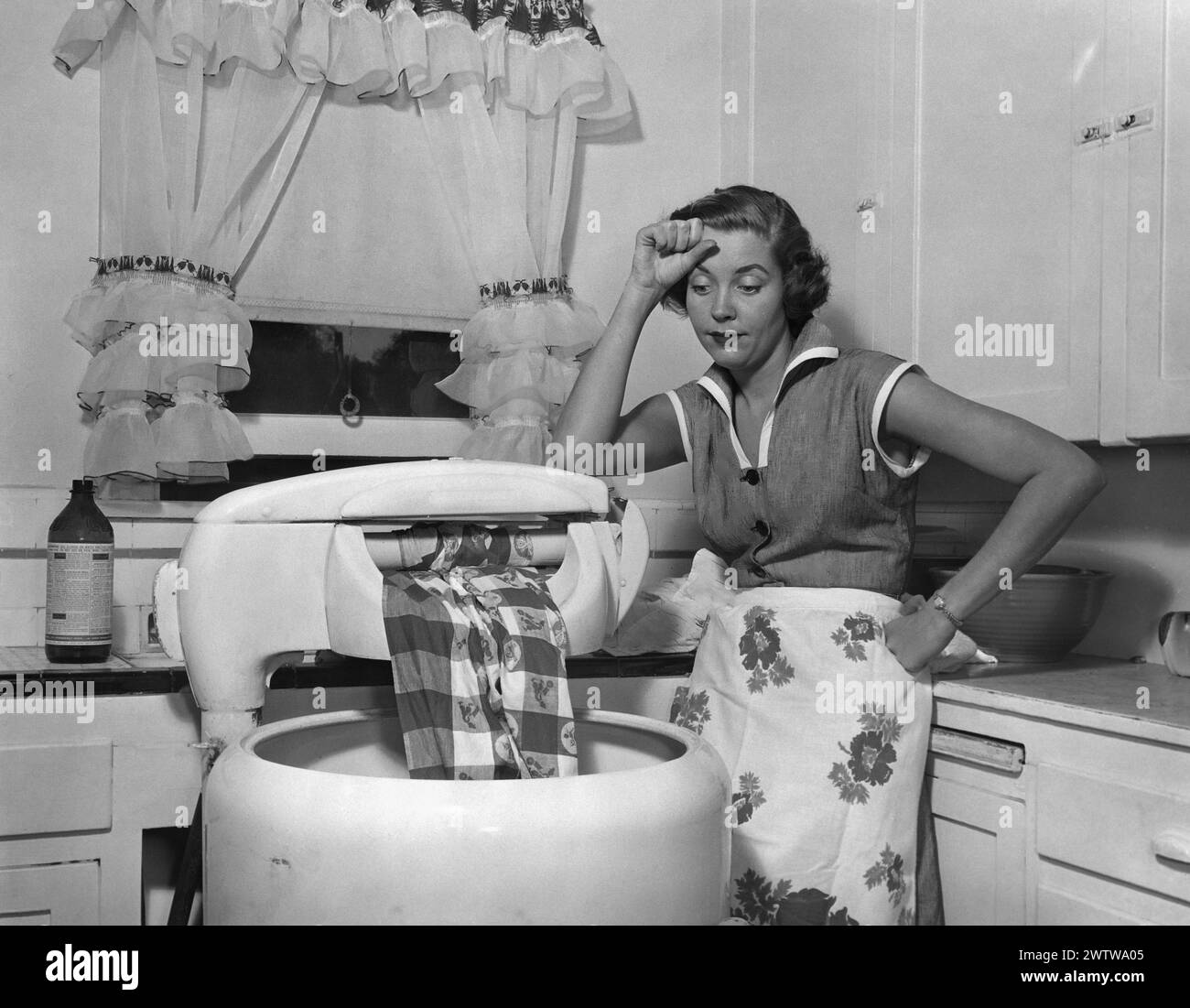 Young woman, welldressed, with an apron on standing her kitchen