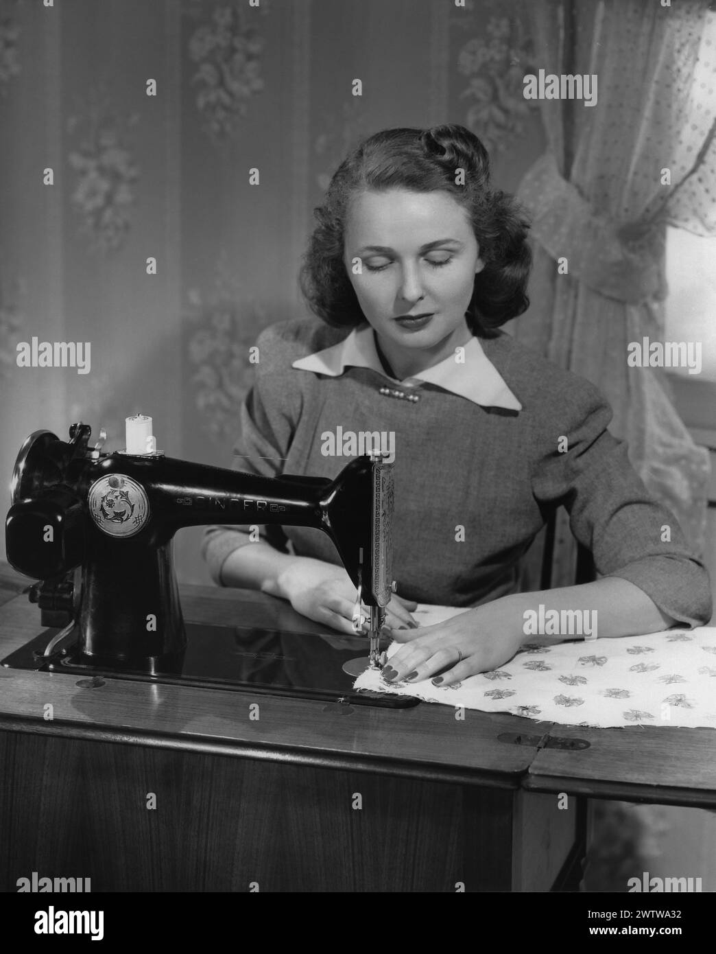 Young woman sitting down and sewing with an electric sewing machine