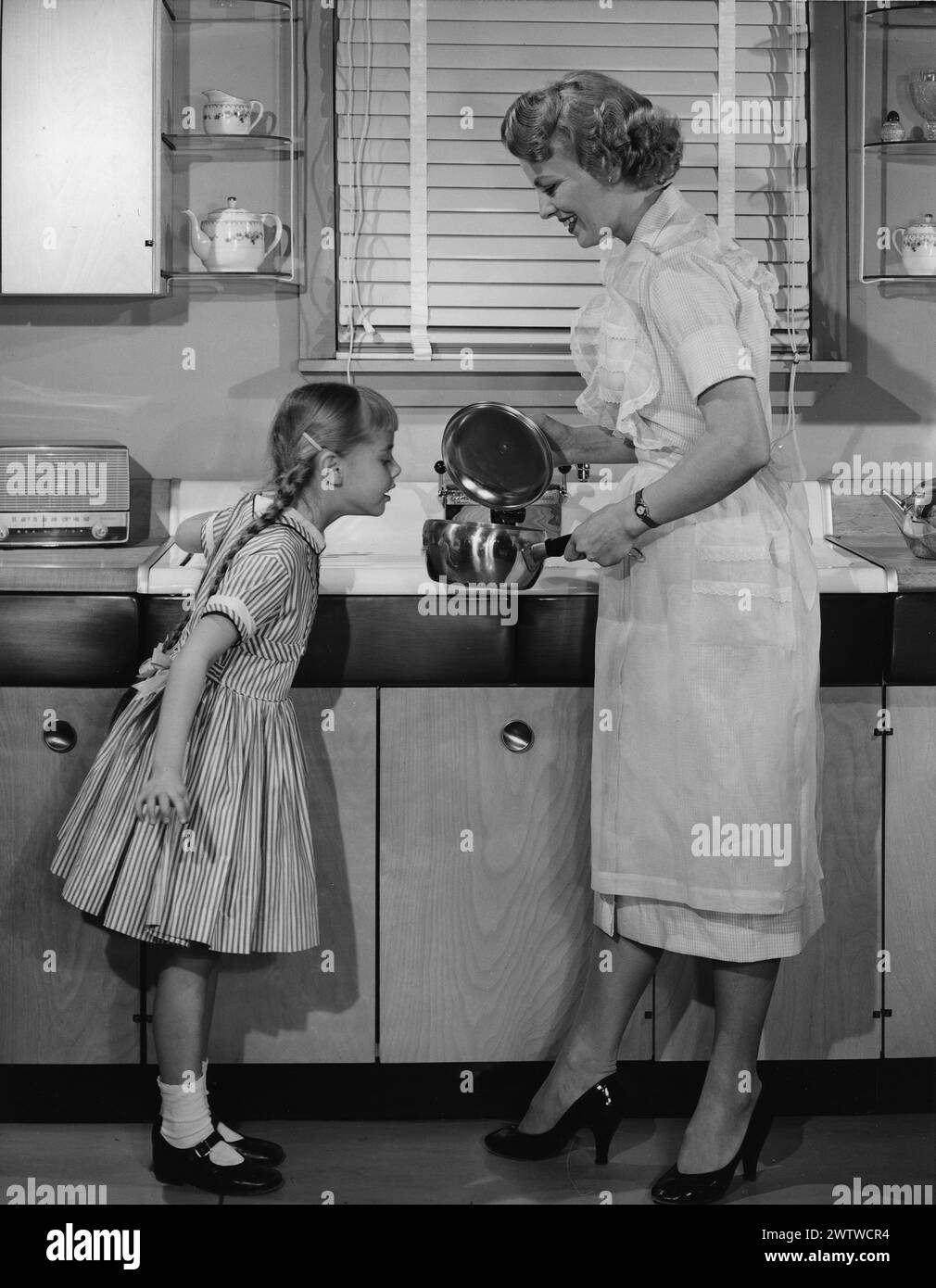 Mom all dressed up, including an apron in high heels standing in front