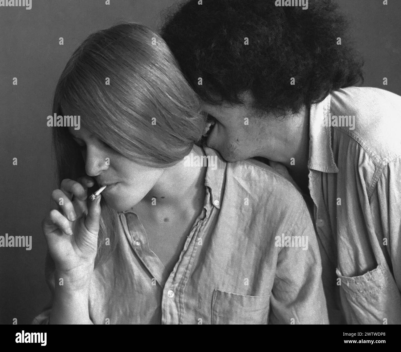 Young long-haired couple smoking weed, man kissing the back of the