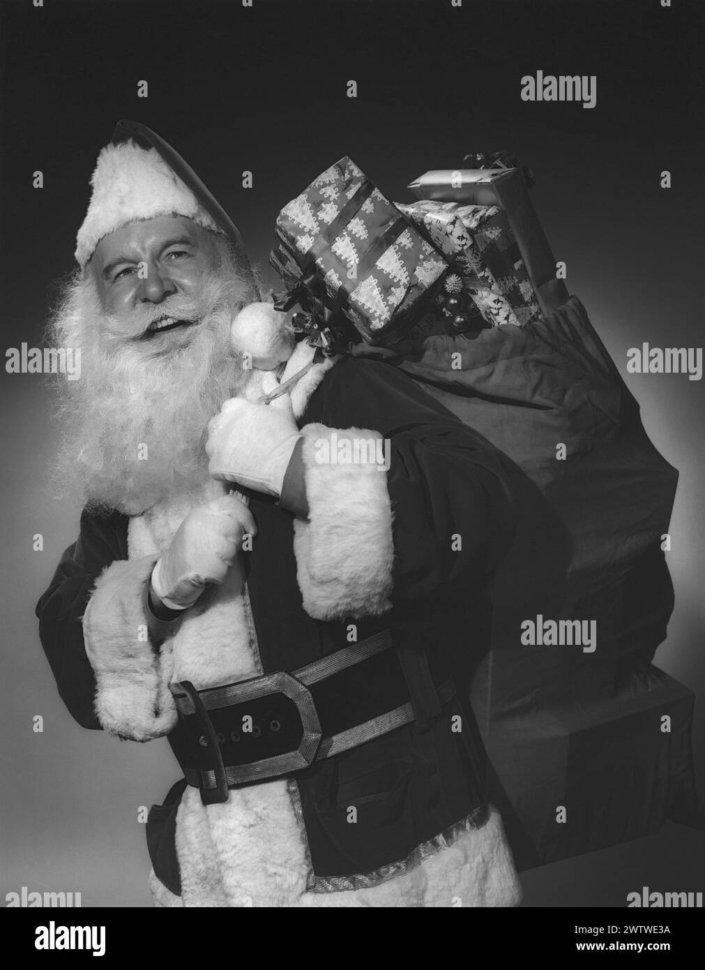 Santa Claus looking back and smiling with a sack of gifts thrown over his shoulder Stock Photo