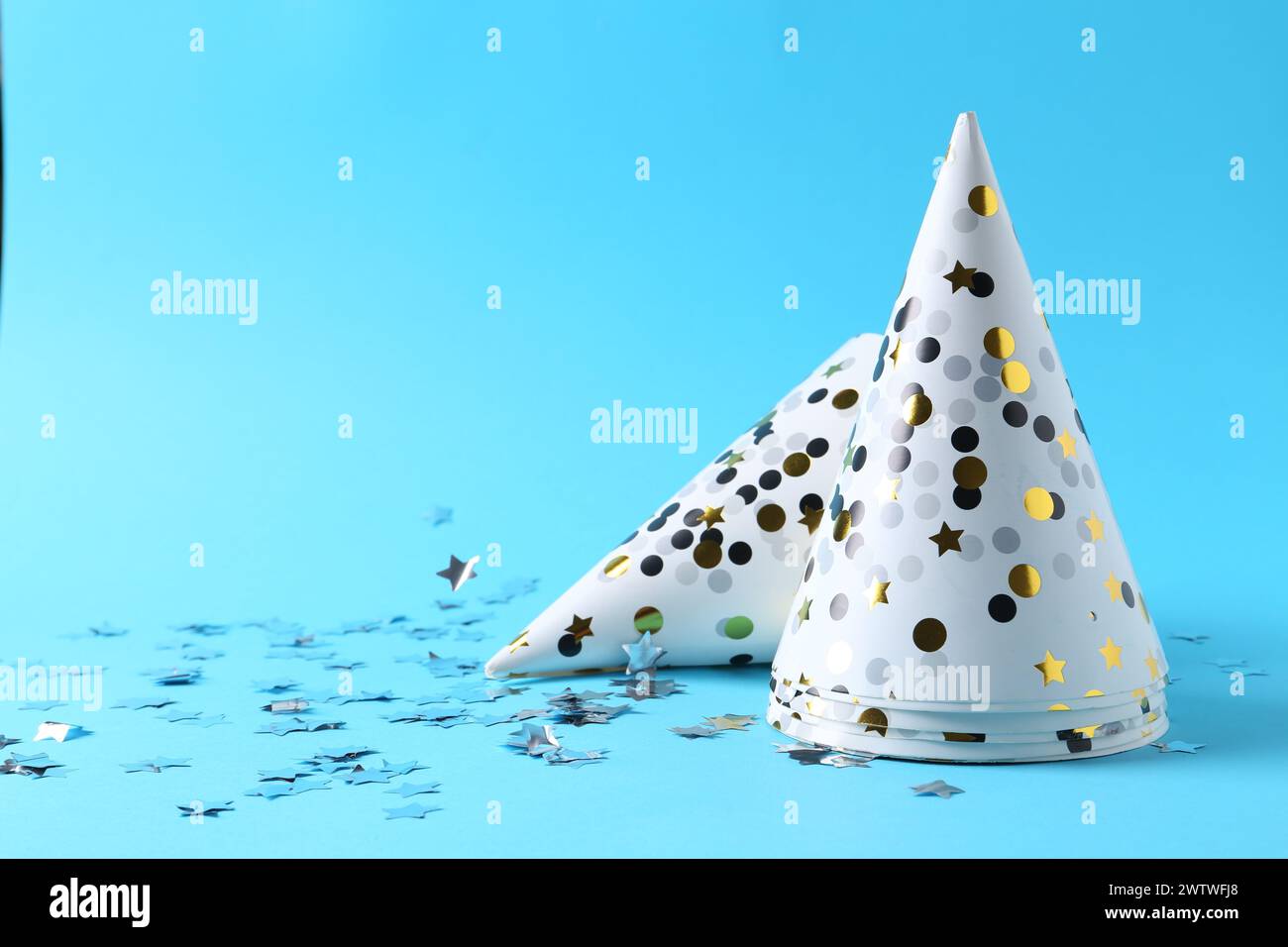 Party hats and confetti on light blue background, space for text Stock ...