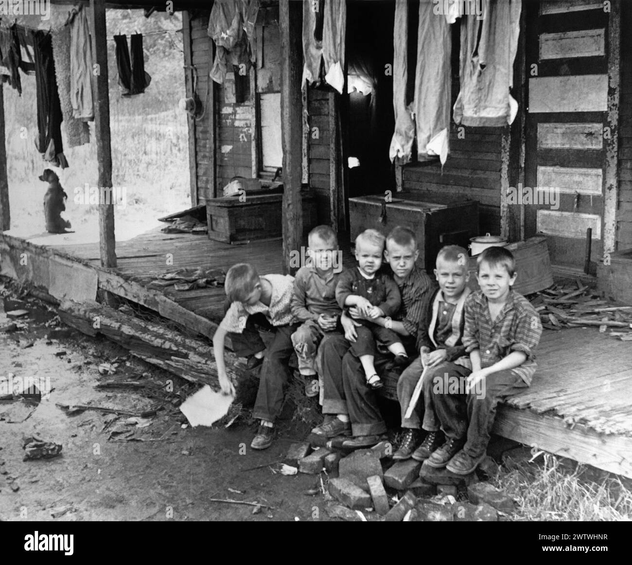 Six young boys sitting in a group on the front porch of a dilapidated home in an Eastern Kentucky mining community Stock Photo
