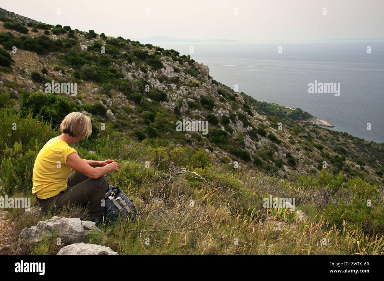 Senior woman sitting on mountain peak with beautiful view on Adriatic sea Stock Photo