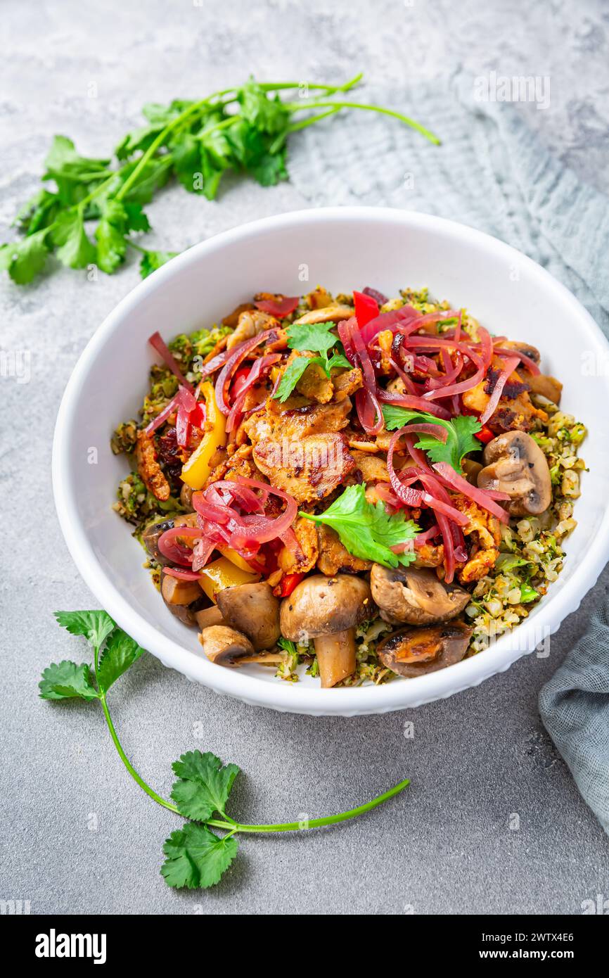 Carb free lunch keto diet. Fried chicken breast with vegetables and mushrooms on cauliflower and broccoli rice. Keto recipe. Stock Photo