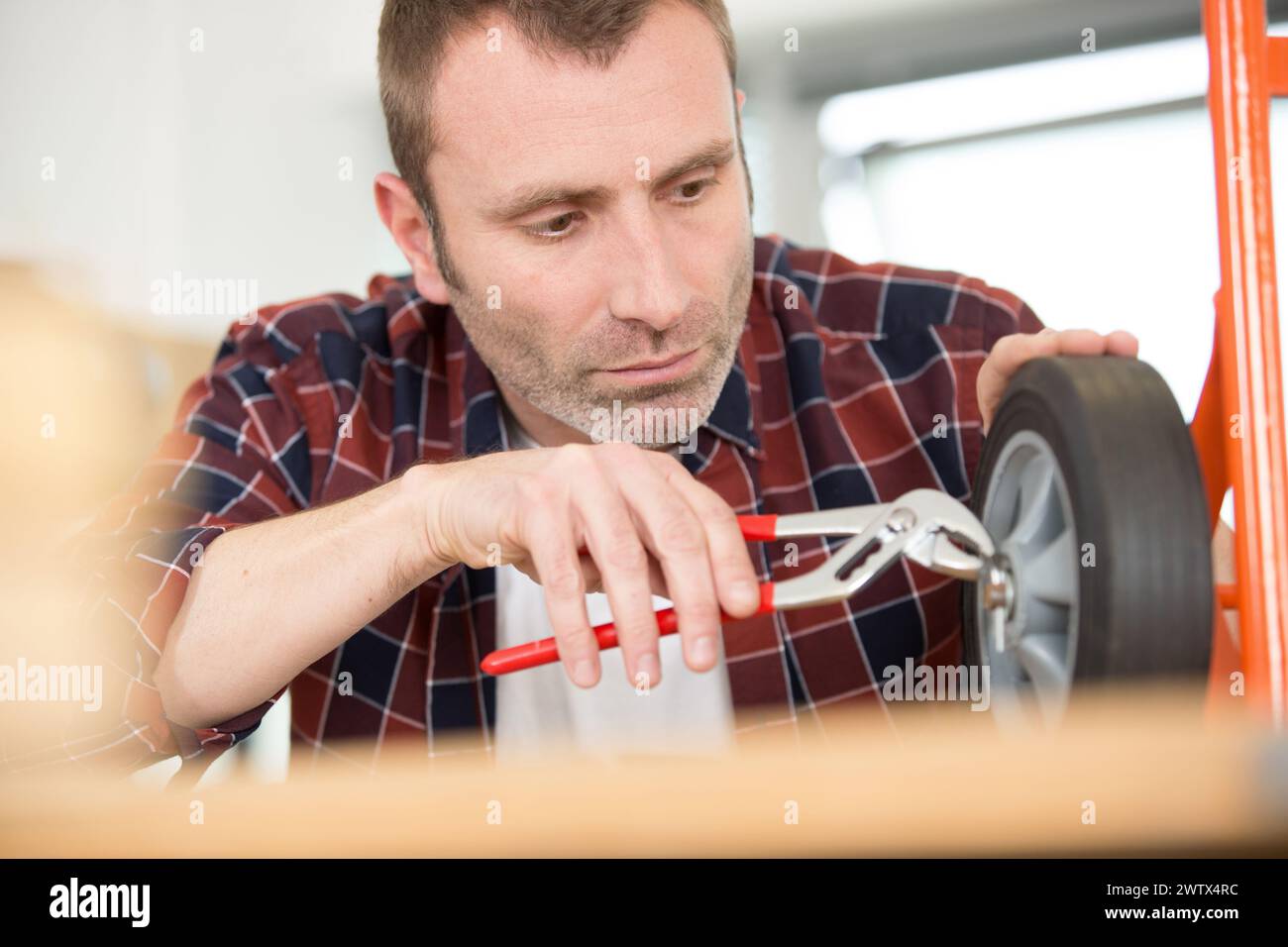 man using a spanner to fix trolley wheel Stock Photo Alamy