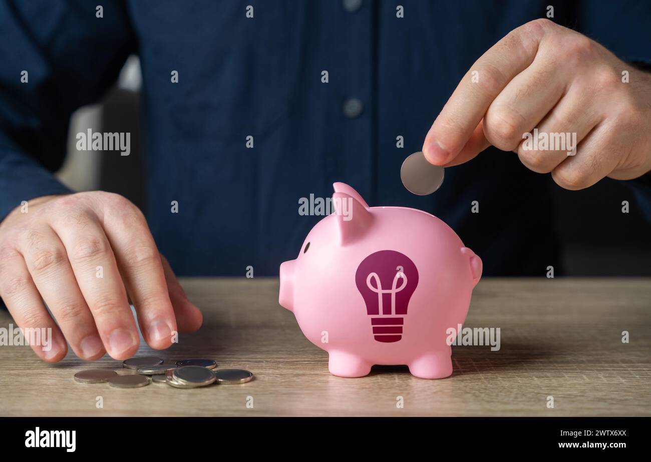 Save up for an idea. A man throws coins into a piggy bank with an idea light bulb symbol. Find investments. Encourage action. Inspire to buy. Invest i Stock Photo