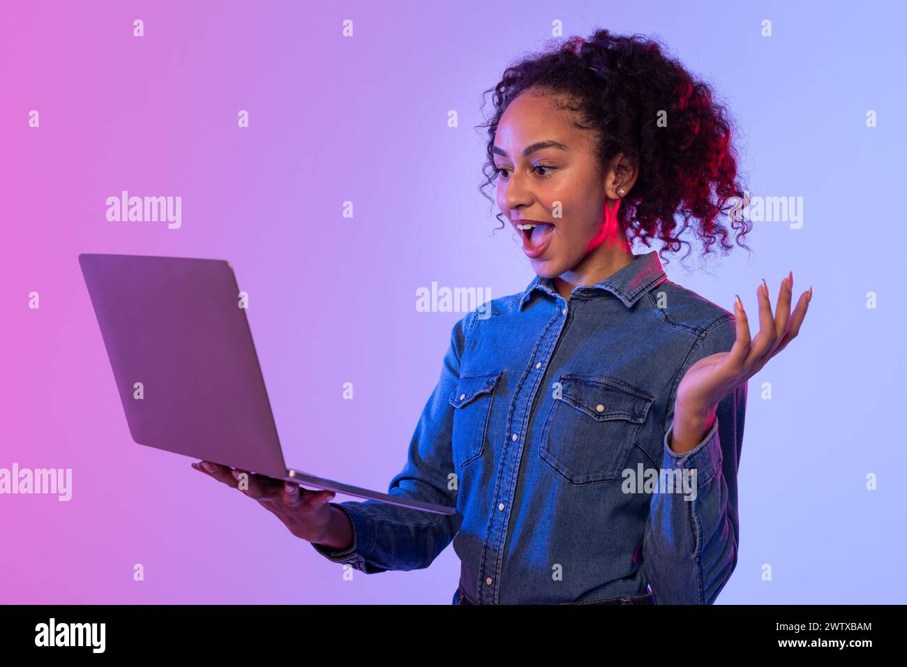 Excited woman with arms open using laptop Stock Photo