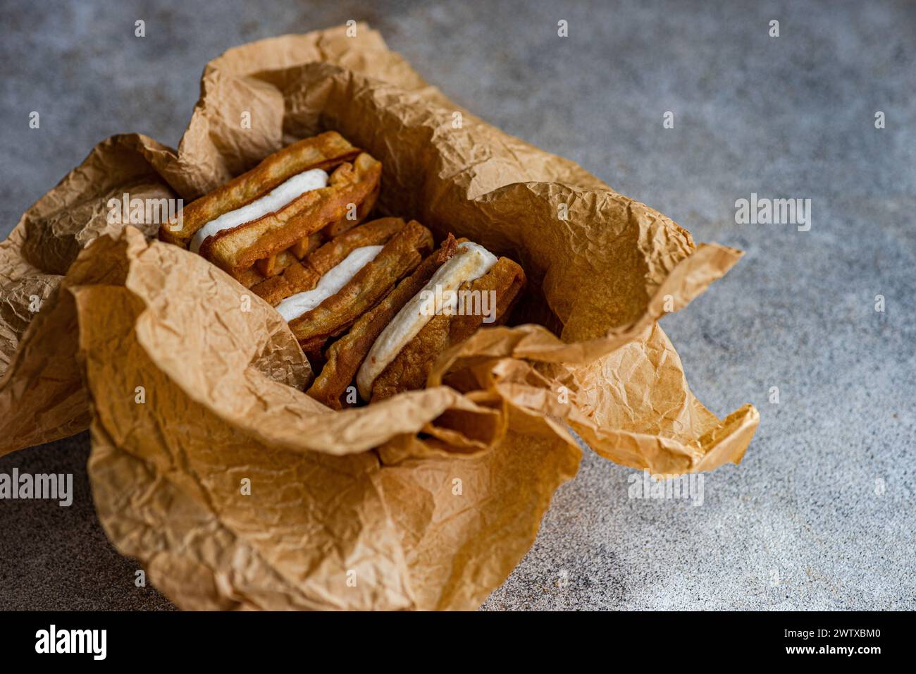 Close-up of  homemade waffles with marshmallows wrapped in baking paper on a table Stock Photo