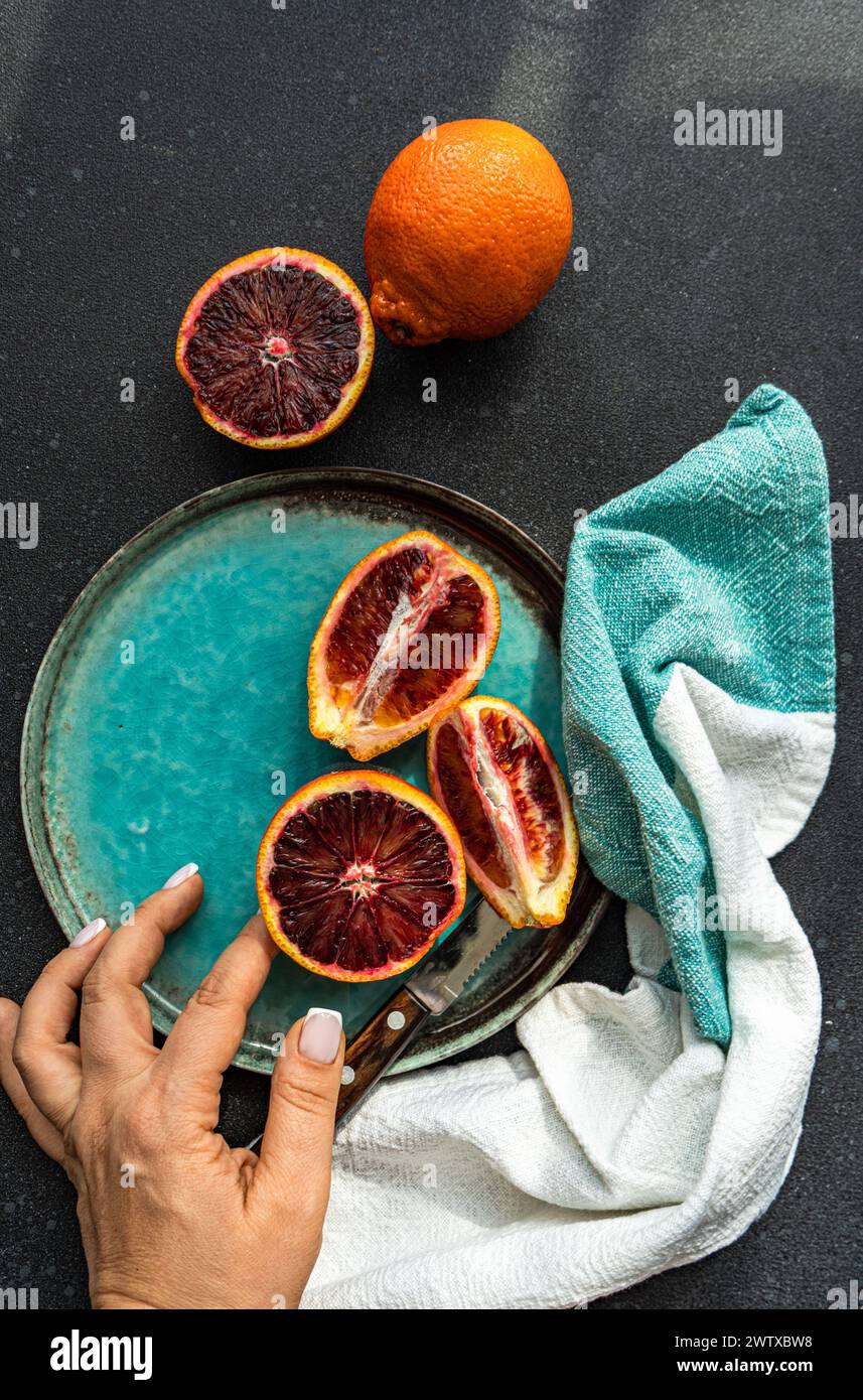 Overhead view of a woman reaching for blood oranges on a plate with a napkin Stock Photo