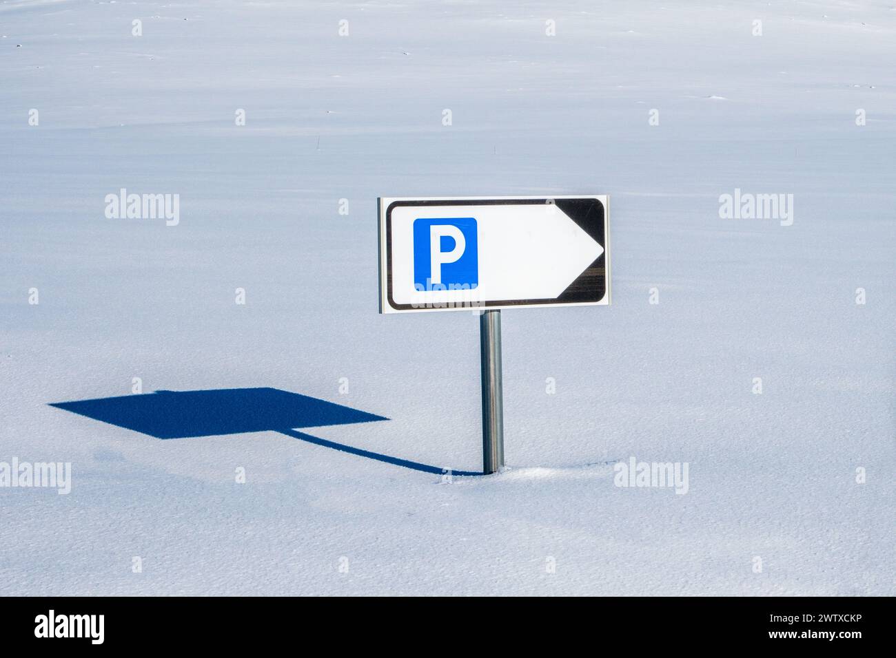 A parking road sign poking out of deep snow on a road buried under snow in Norway Stock Photo