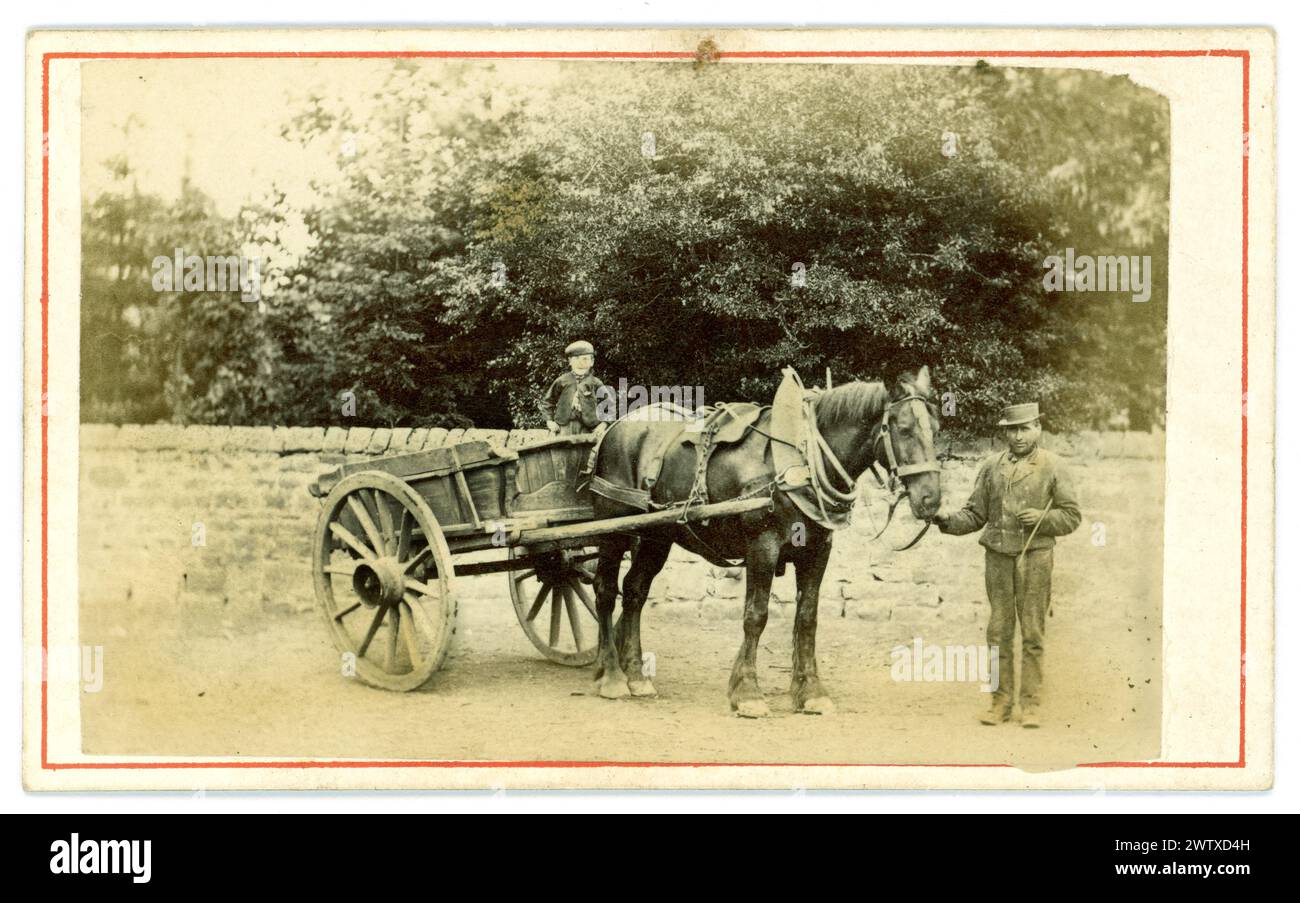 Original Victorian carte de visite (visiting card or CDV) of country image of long ago, a rustic farmhand standing next to a Victorian horse and cart, with a young boy, possibly his son, taking a ride in the cart. Circa 1860's. U.K. Stock Photo