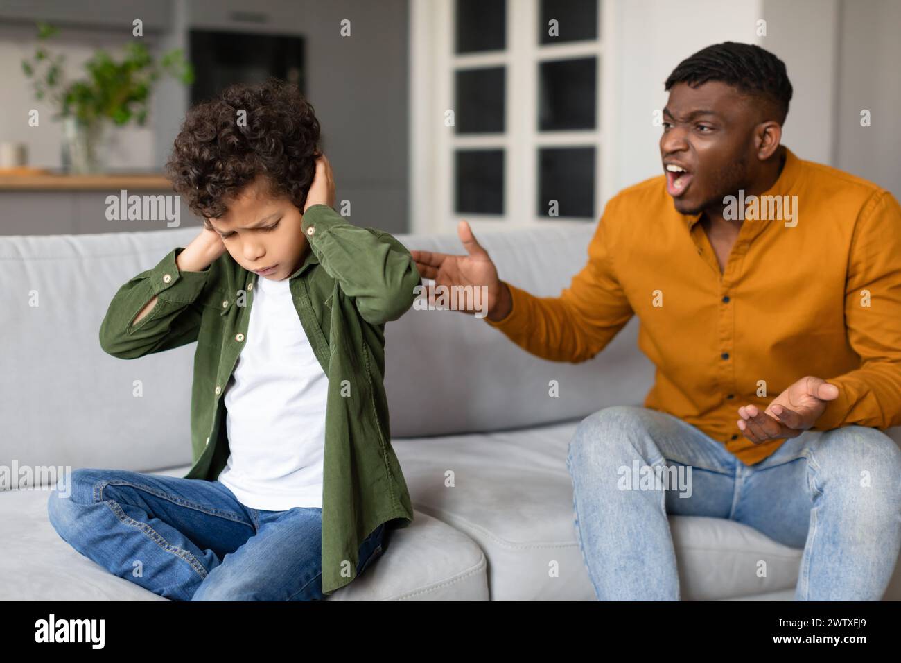 Son covering ears while dad shouts in frustration Stock Photo - Alamy