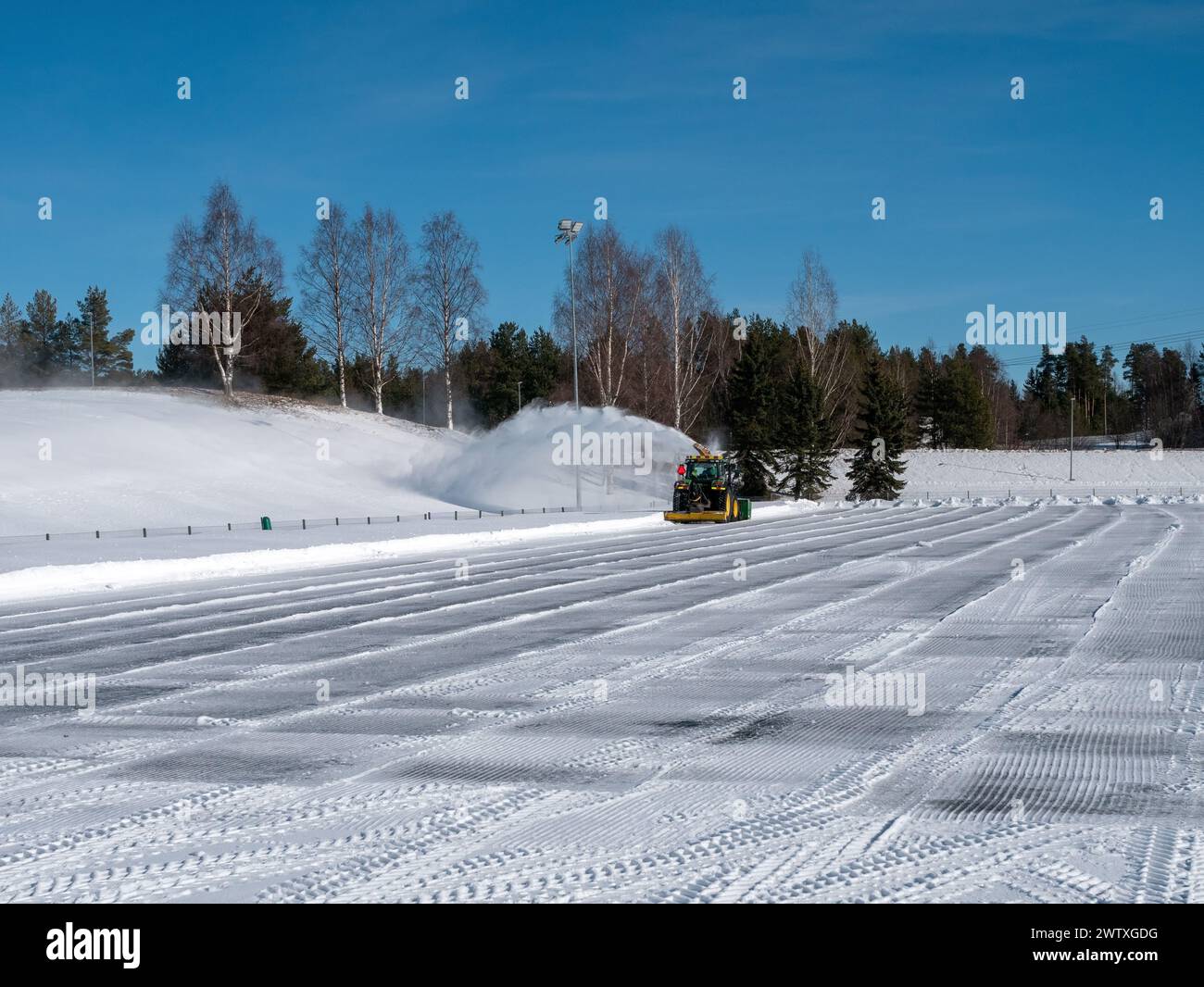 Tractor with snowblower blowing snow on a sports area, Kempele Finland Stock Photo