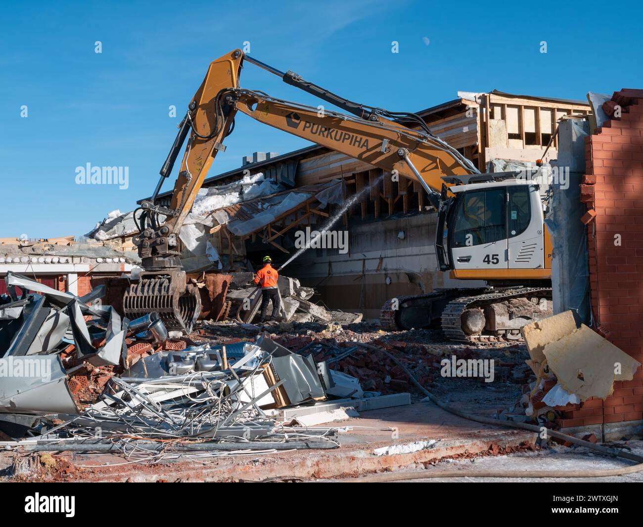 Workman spraying water over a demolition site in Kempele, Finland Stock Photo
