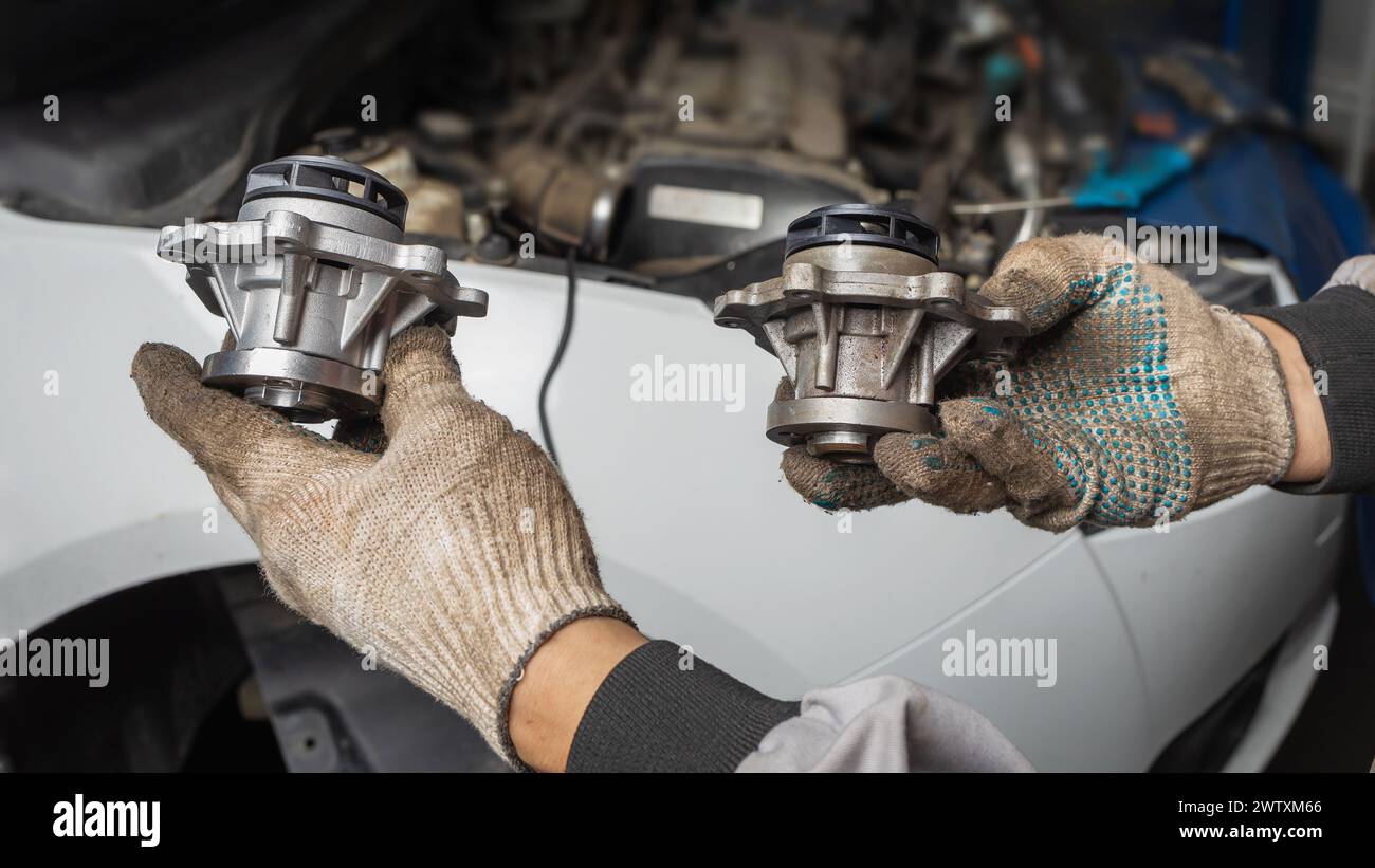 An auto mechanic holds a new and old car engine pump in his hands Stock Photo
