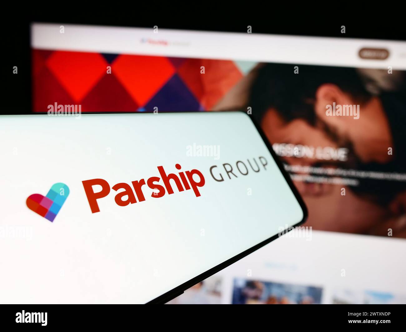 Cellphone with logo of German online dating company ParshipMeet Holding GmbH in front of business website. Focus on center-left of phone display. Stock Photo