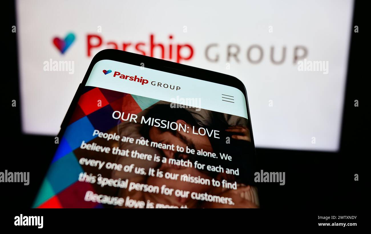 Mobile phone with website of German online dating company ParshipMeet Holding GmbH in front of business logo. Focus on top-left of phone display. Stock Photo