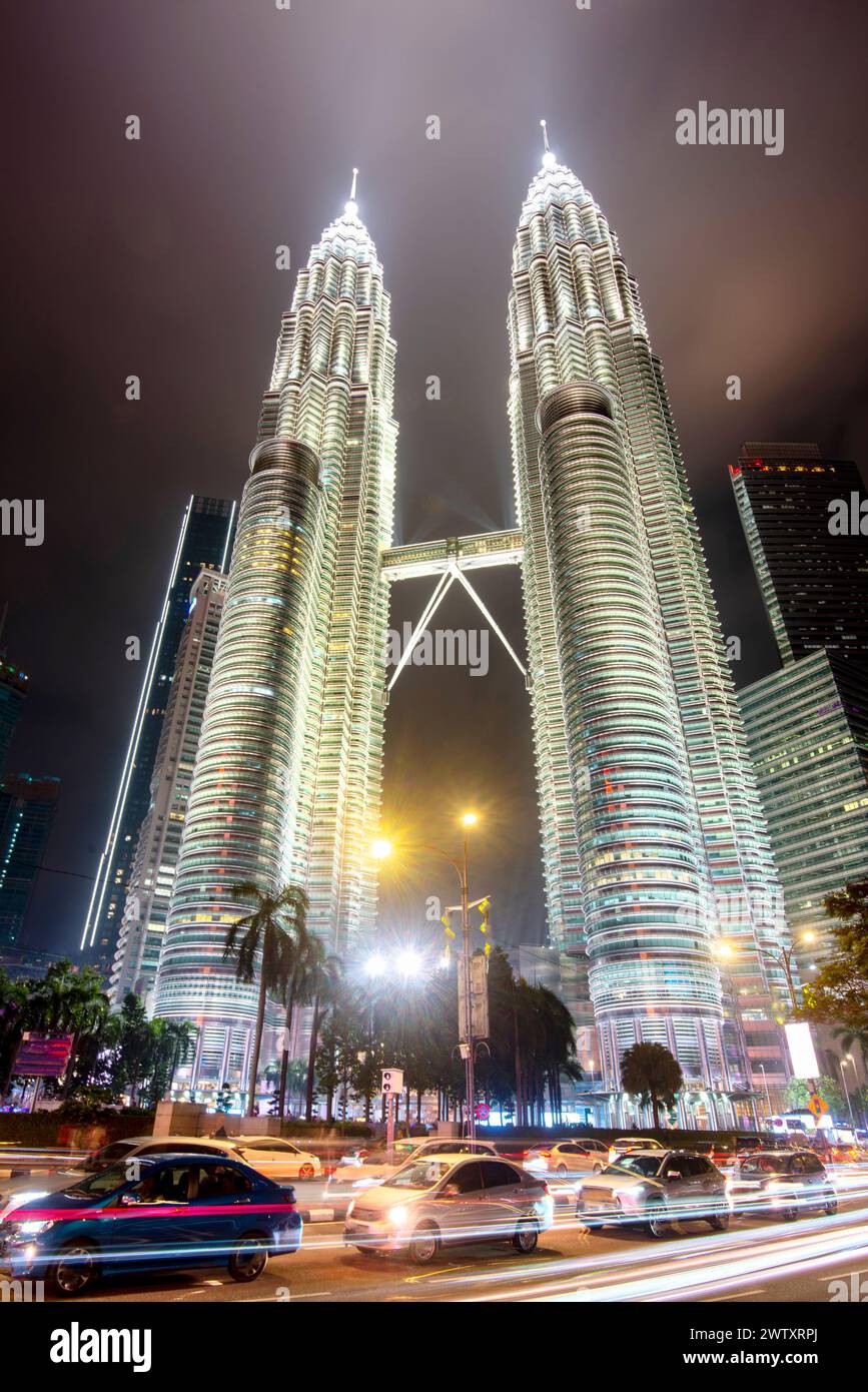 Iconic Malaysian buildings, a major landmark,Illuminated in a silvery light against the evening sky,with blurred movement,streaking cars lights in nig Stock Photo