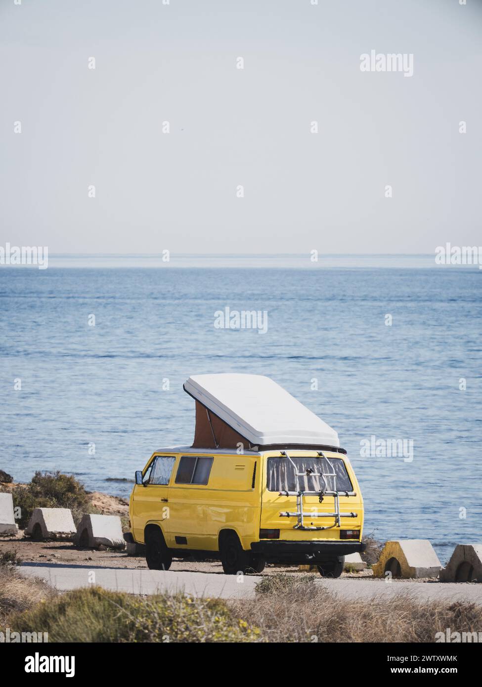 Yellow vintage camper van with pop-up roof parked by the sea Stock ...