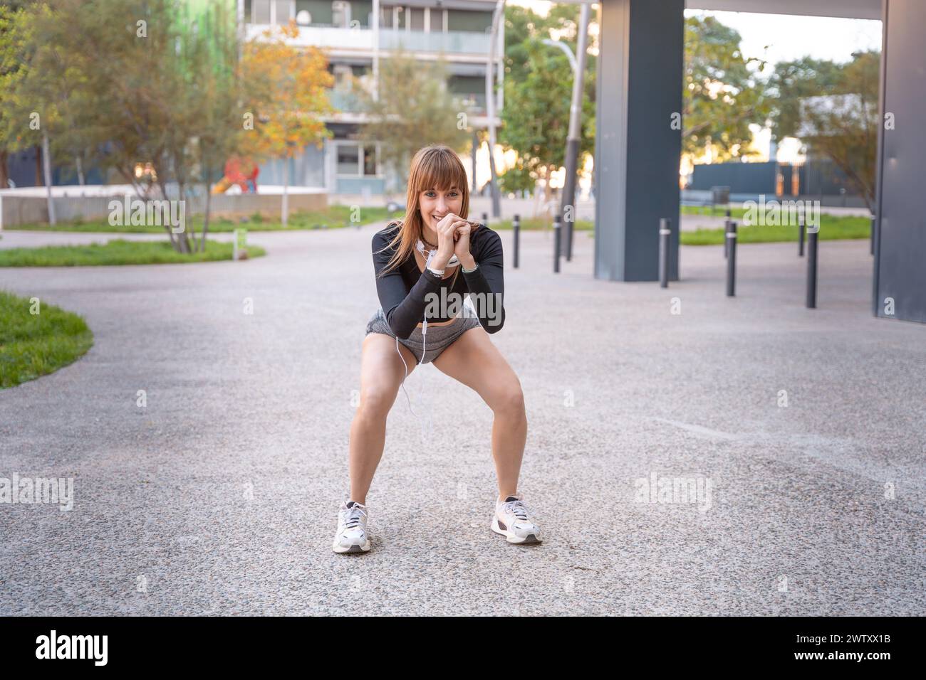 Active and fit female athlete doing squat exercise outdoors. Stock Photo