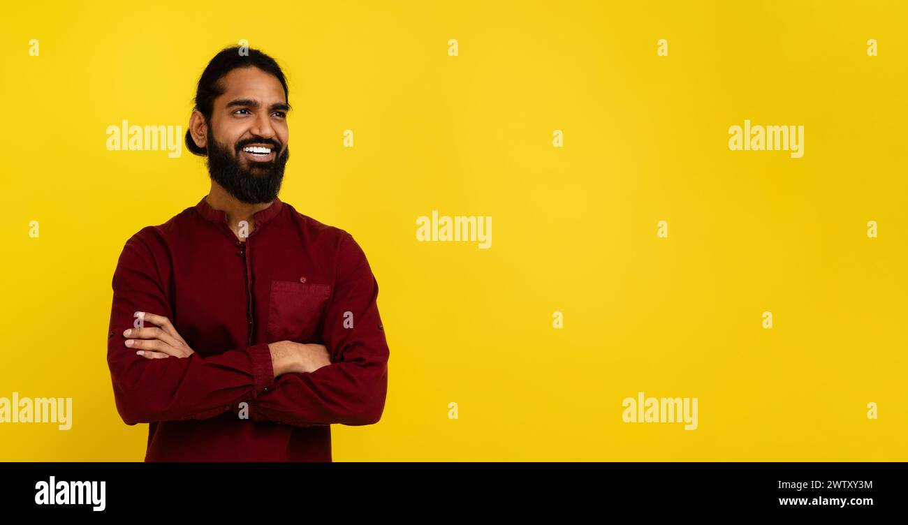 Confident indian guy looking at copy space on yellow Stock Photo