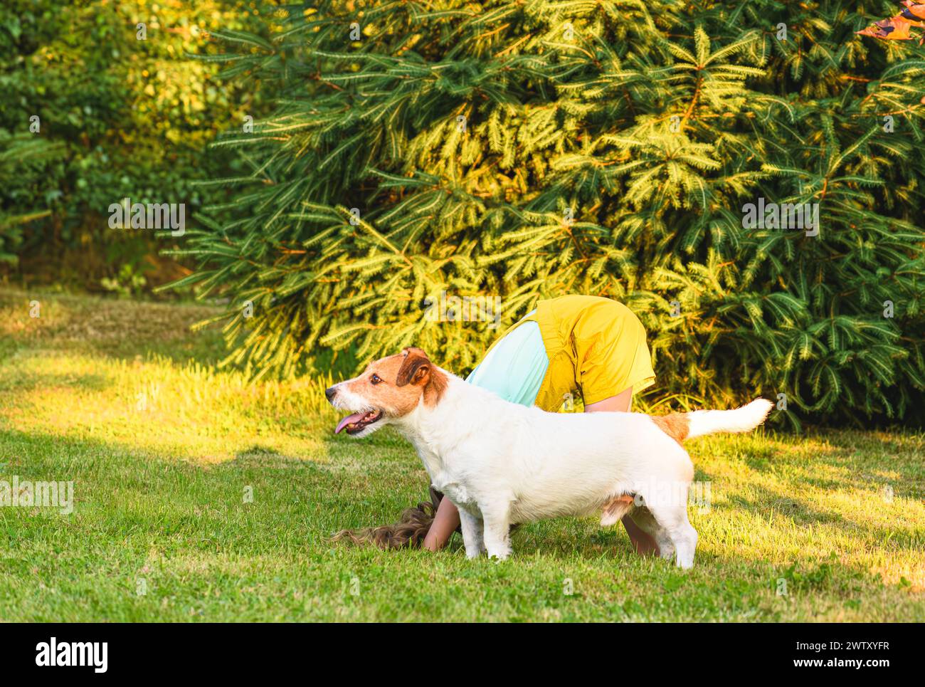 Kid doing yoga exercise outdoors is standing in dog pose Stock Photo