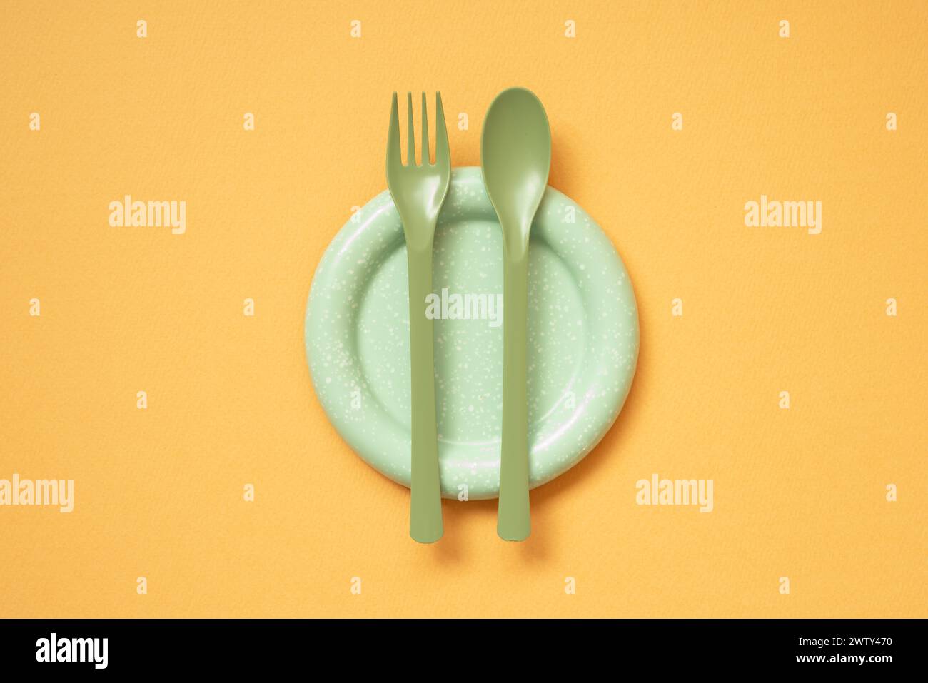 Empty green plate and cutlery on orange table background. flat lay, top view Stock Photo