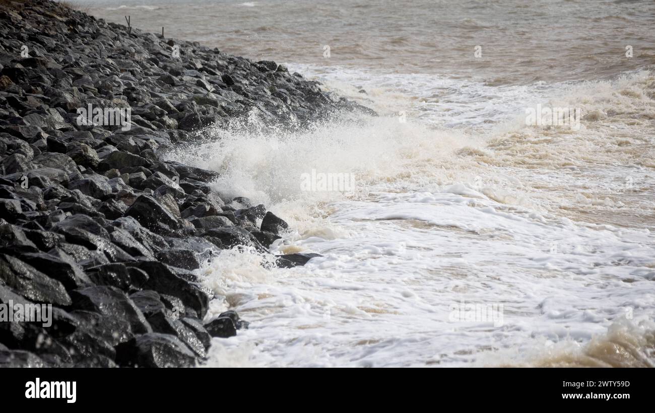 Waves crash on granite stones during a storm on the Black Sea coast. City embankment on a cloudy winter day in Odessa Stock Photo
