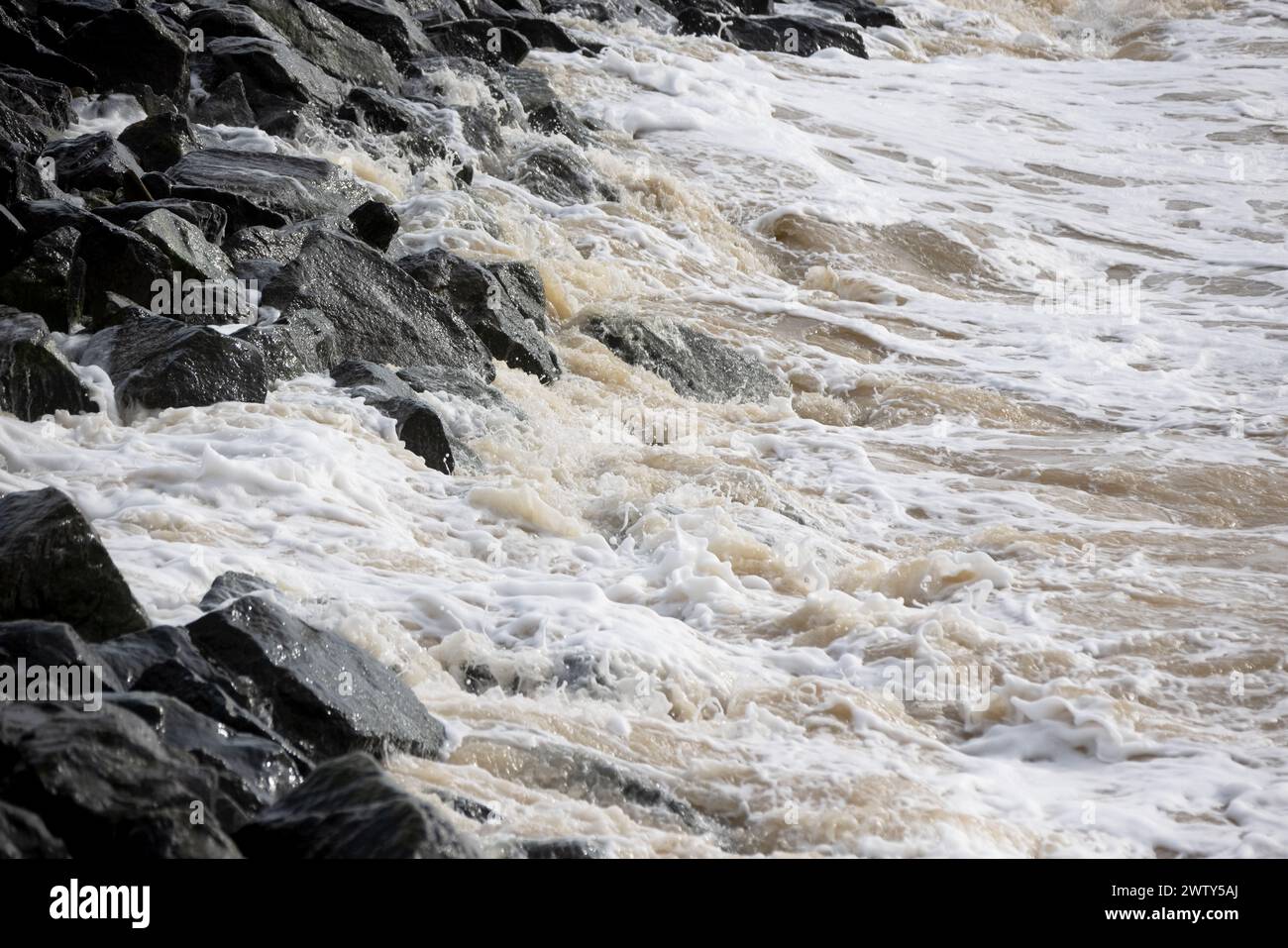 Waves crash on granite stones during a storm on the Black Sea coast. City embankment on a cloudy winter day in Odessa Stock Photo