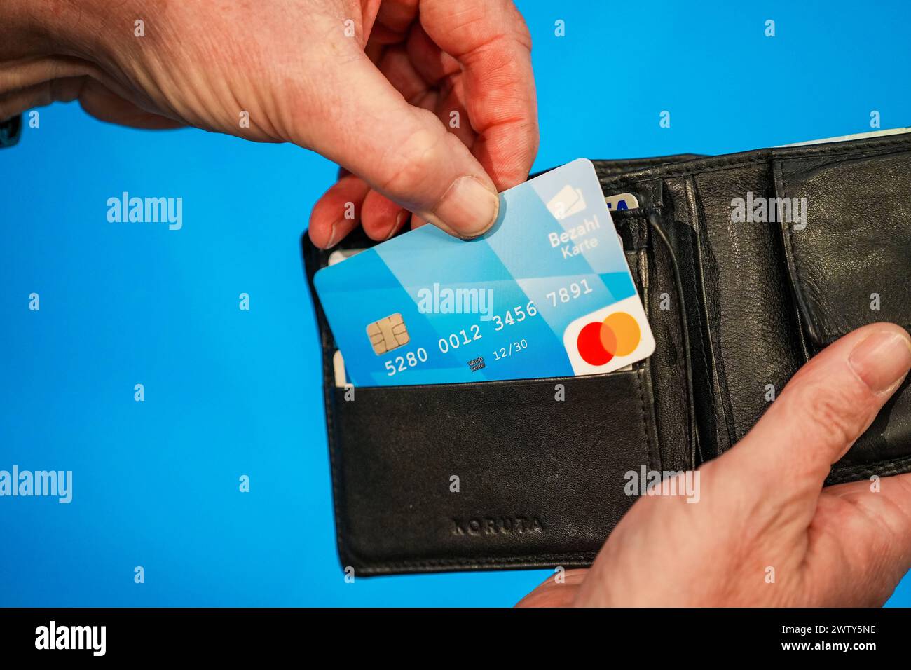 Munich, Bavaria, Germany - March 20, 2024: A hand holds a wallet with the new Bavarian payment card for asylum seekers which was presented at the press conference on March 20 in Munich *** Eine Hand hält eine Geldbörse mit der neuen bayerischen Bezahlkarte für Asylbewerber welche auf der Pressekonferenz vom 20 März in München vorgestellt wurde Stock Photo