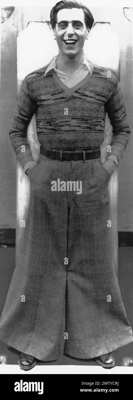 Actor George Givot from 'The Singing Fool ' stands with his hands in his trouser pockets. He is wearing bell bottom pants Stock Photo