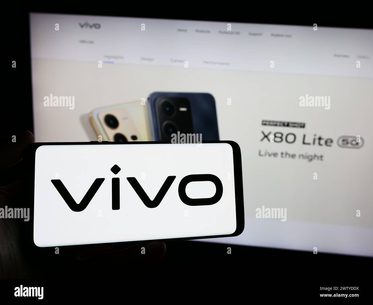 Person holding smartphone with logo of Chinese company Vivo Communication Technology Co. Ltd. in front of website. Focus on phone display. Stock Photo