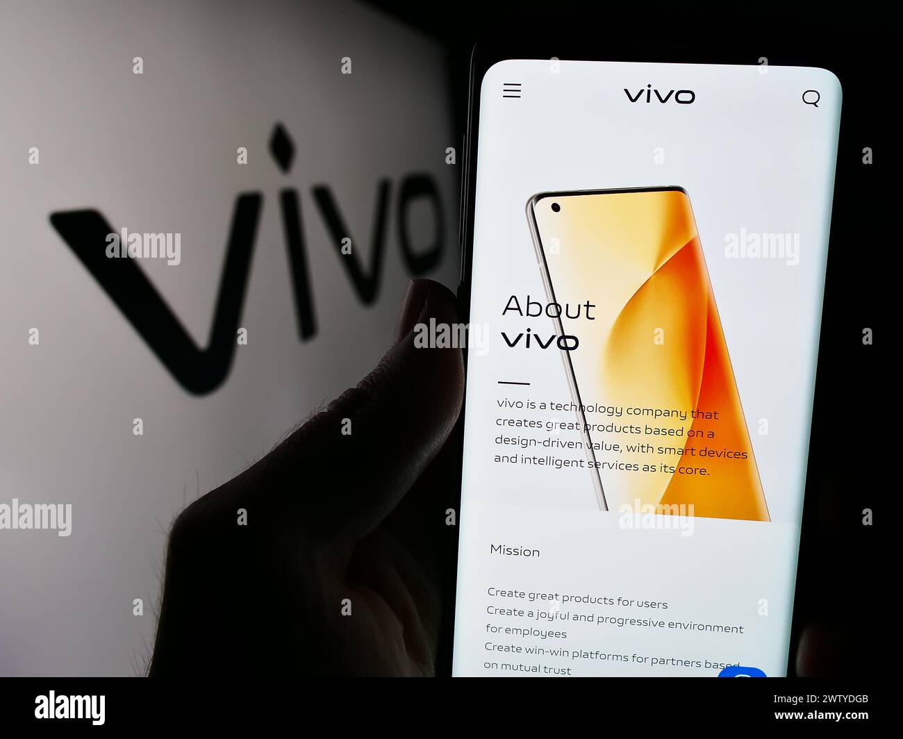 Person holding cellphone with website of Chinese company Vivo Communication Technology Co. Ltd. with logo. Focus on center of phone display. Stock Photo