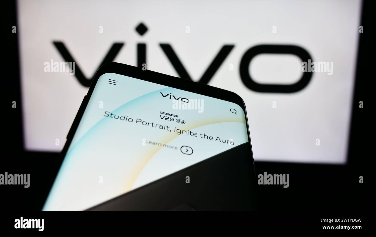 Smartphone with webpage of Chinese company Vivo Communication Technology Co. Ltd. in front of business logo. Focus on top-left of phone display. Stock Photo