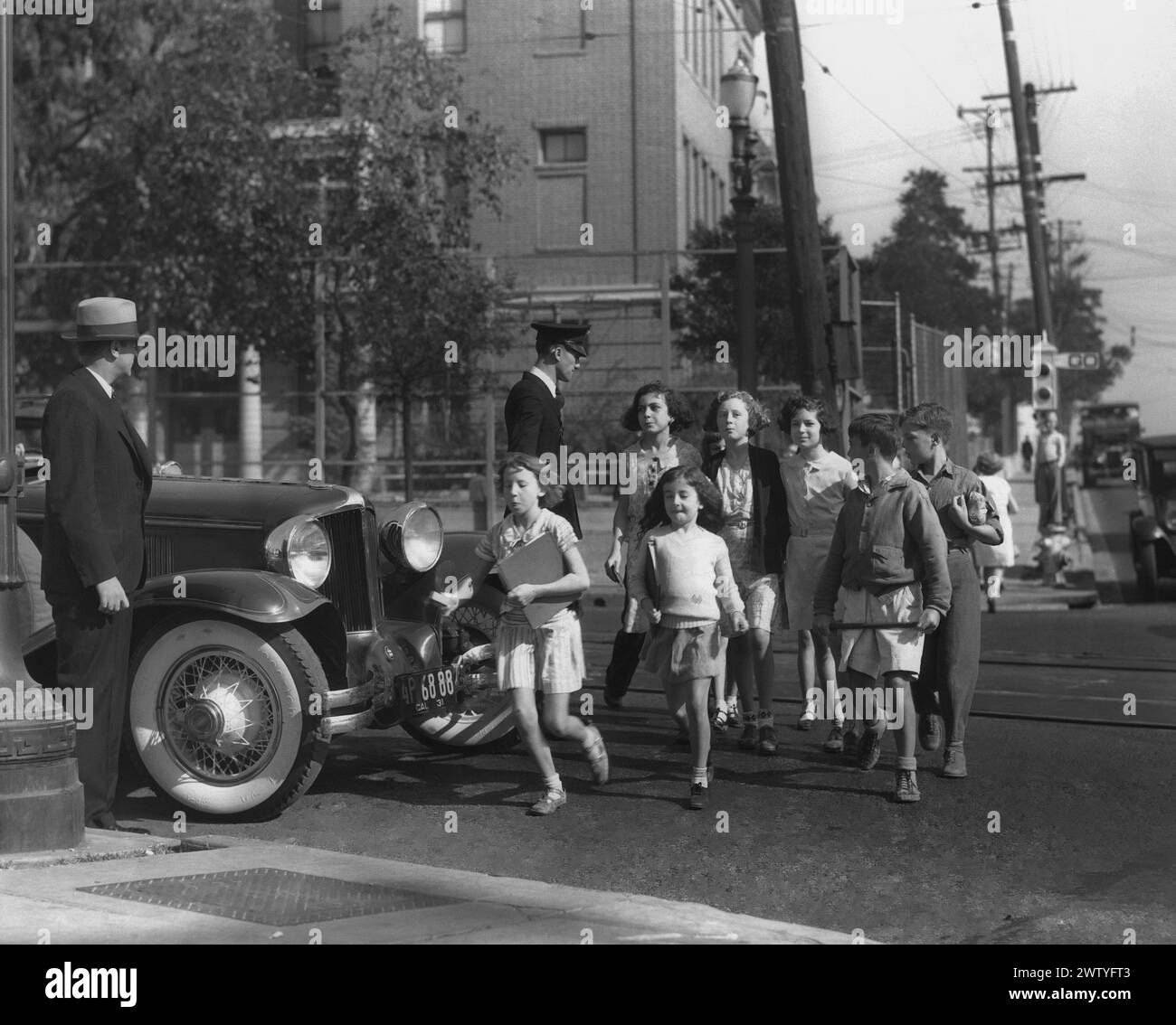 A group of Boys and Girls Club cross the street under the watchful gaze of a road safety guard Stock Photo