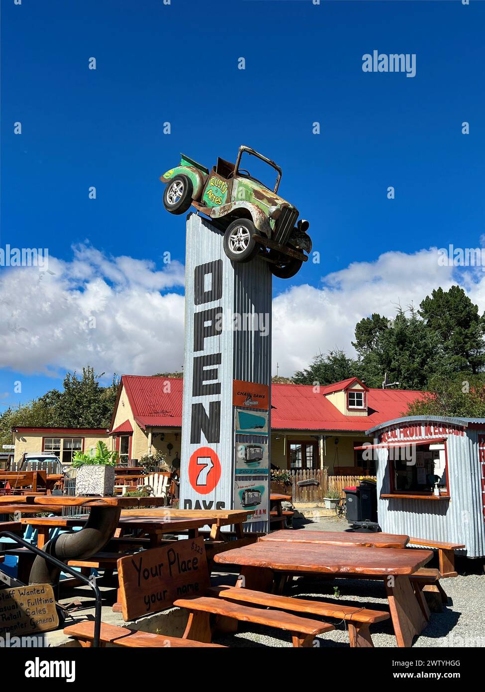 Vintage old car on top of a junk yard sign indicating it is open for business Stock Photo