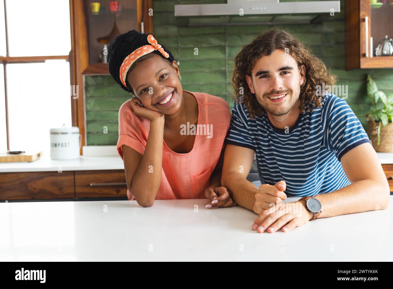 A diverse couple shares a joyful moment in the kitchen at home Stock Photo