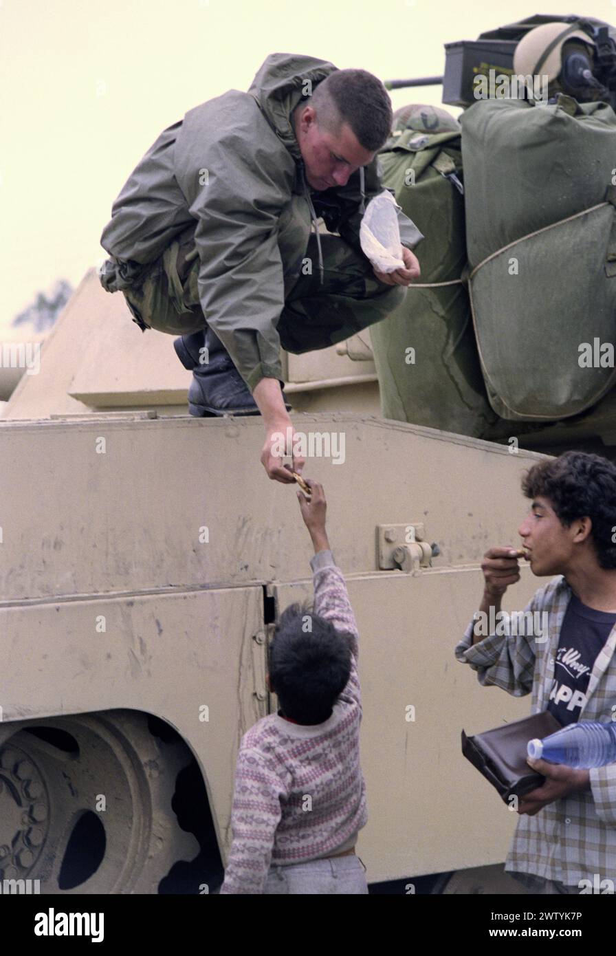 First Gulf War: 23rd March 1991 A U.S. Army soldier gives candy to Iraqi children in a refugee camp near Safwan in southern Iraq, close to the border with Kuwait. Stock Photo