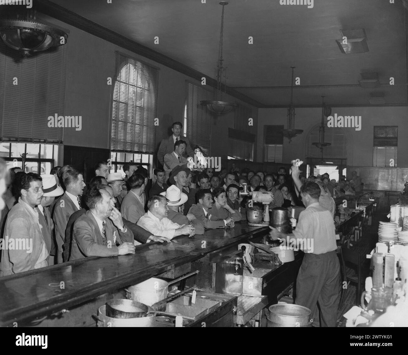 Interior of a crowded bar, mostly men, but a few women huddled up to the bar five deep Stock Photo