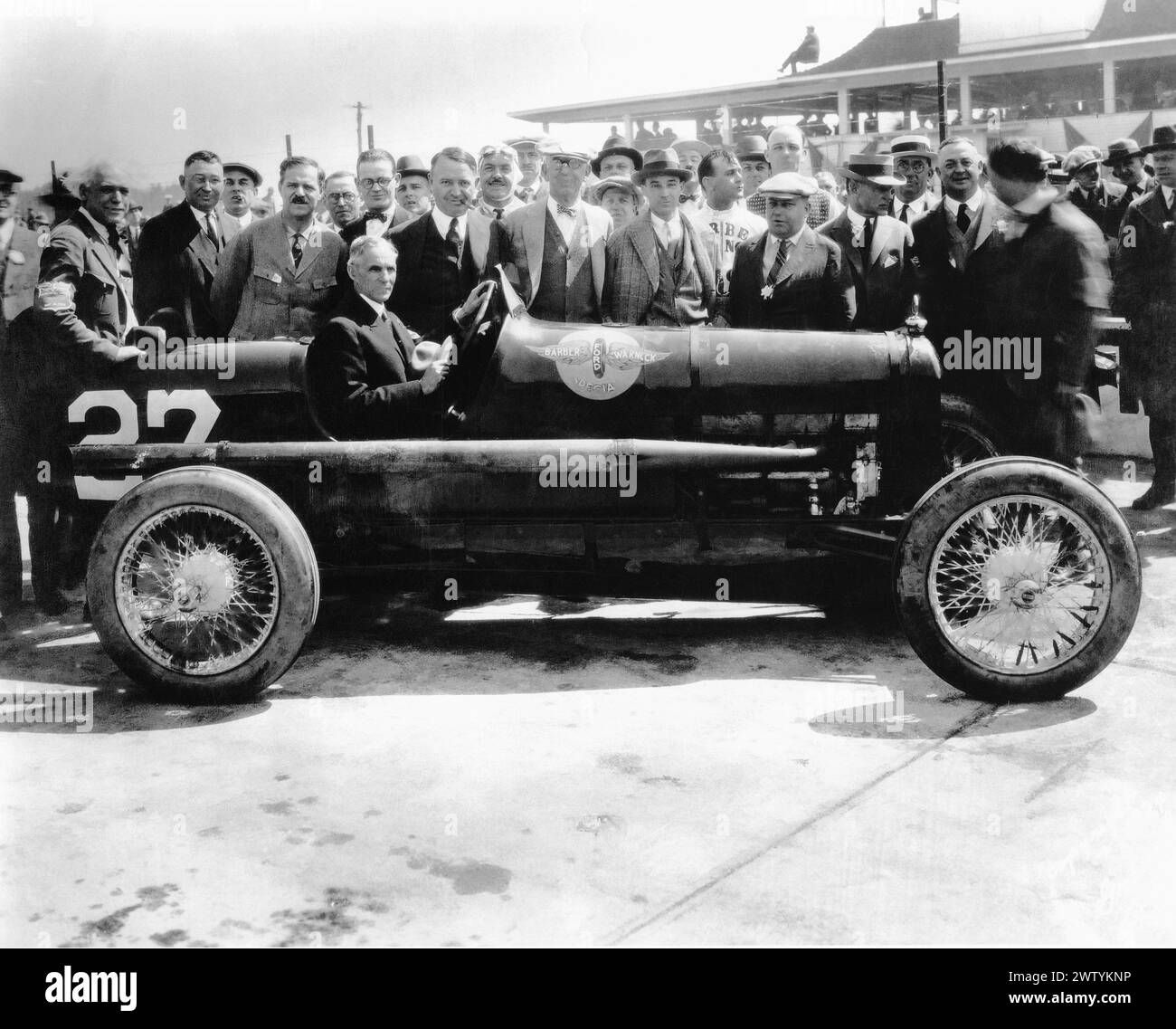 Henry Ford sitting in the Barber-Warnick Special race car at Indianapolis motor Speedway With crowd of people around him Stock Photo